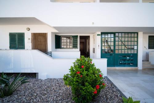 a white house with a green door and a bush at Apartment Wolf in Lourinhã