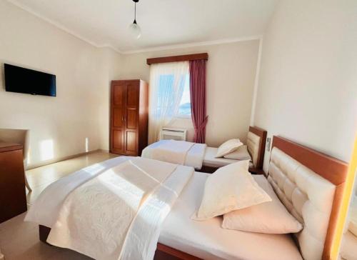 a bedroom with two white beds and a window at Hotel Kanione in Çorovodë