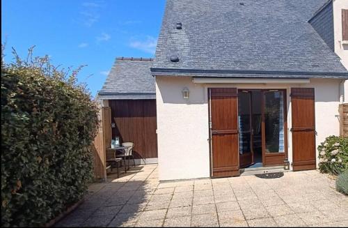 エルドゥヴァンにあるMaison de plage avec piscine Erdeven-Carnacの木製のドアとパティオが備わる小さな家
