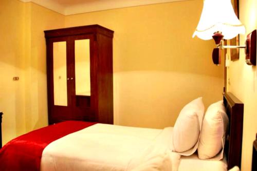 a bedroom with a bed with a red blanket and a lamp at Alexandria Mediterranean Suites in Alexandria