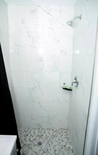 a bathroom with a shower with a white wall at Rainbow Motel in Douglassville