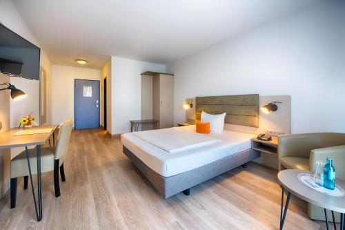 a hotel room with a bed and a table and chairs at ACHAT Hotel Zwickau in Zwickau