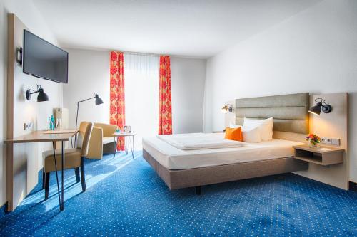a hotel room with a bed and a desk at ACHAT Hotel Zwickau in Zwickau