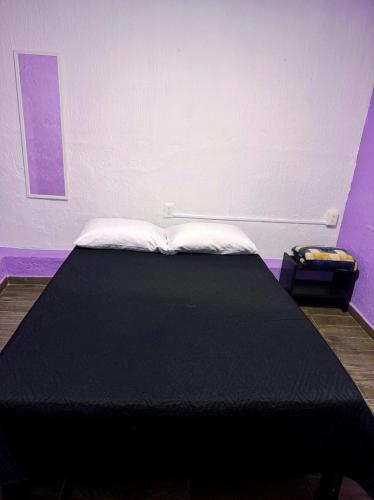 a black bed in a room with purple walls at Alo México in Mexico City