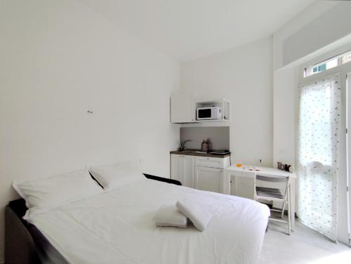 a white bedroom with a bed and a microwave at Residence Mario Bianco in Milan