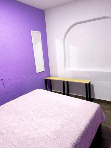 a bedroom with a bed and a purple wall at Alo México in Mexico City