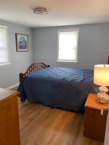 a bedroom with a blue bed and two windows at Willows Cottage East in Dennis Port