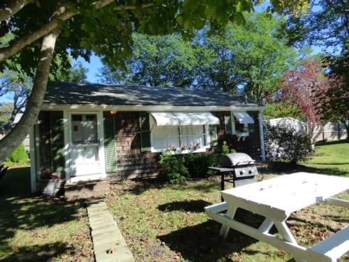ein kleines Haus mit einem Picknicktisch im Hof in der Unterkunft Willows Cottage East in Dennis Port