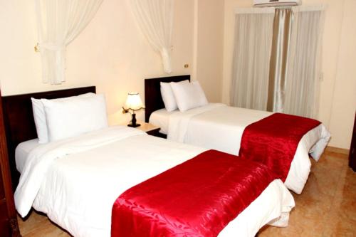 two beds in a hotel room with red blankets at Alexandria Mediterranean Suites in Alexandria