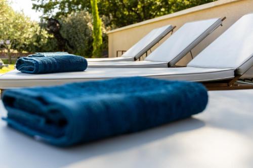 a row of lounge chairs with blue cushions on a table at La Villa Sable en Provence in Saint-Saturnin-lès-Apt