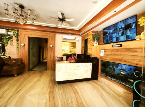 a person sitting in a living room with a fish tank at Shri Shyam Luxury Hotel in Har Ki Paudi in Haridwār