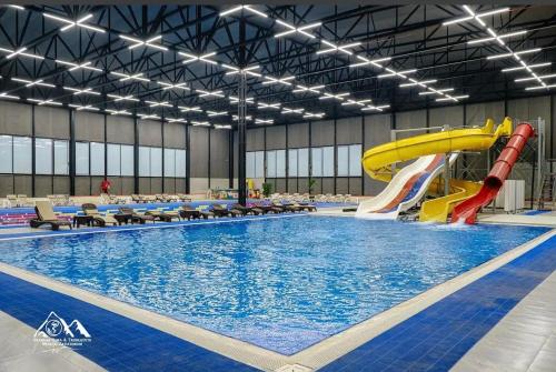 a large swimming pool with a water slide in a building at The River View Villa الحلال Halal Concept in Quba