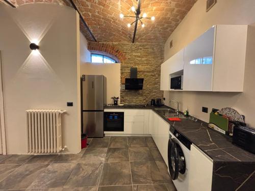 a kitchen with white cabinets and a brick wall at Relais Portaluna delle Langhe in Mango