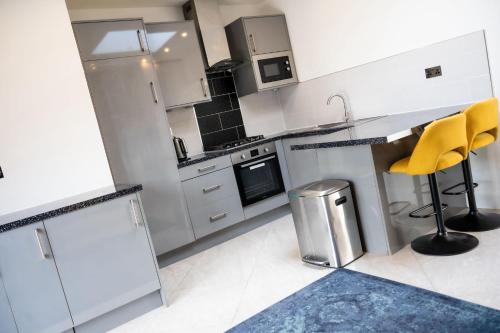 una cocina con electrodomésticos de acero inoxidable y sillas amarillas en Delightful 1-Bedroom Apartment with Garden, en South Norwood