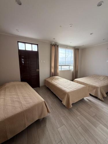 a bedroom with two beds and a window at Laguna Azul Tacna in Tacna
