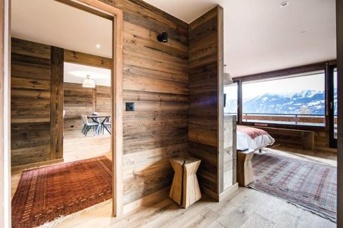 a room with wooden walls and a bedroom with a window at La Ruinette-stylish 2-bed With Pool & Gym Access in Verbier