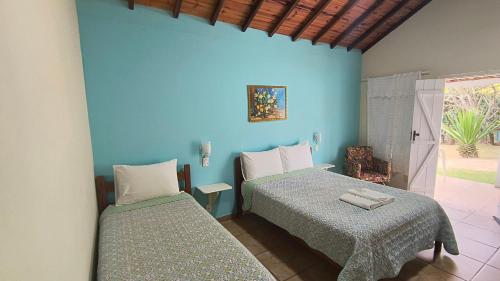 two beds in a room with blue walls at Pousada Recanto do Sossego in São Thomé das Letras