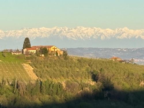 a house on a hill with mountains in the background at Relais Portaluna delle Langhe in Mango