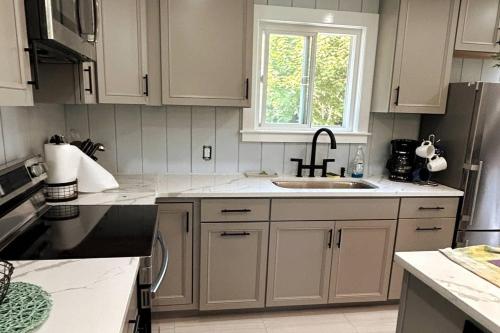 a kitchen with white cabinets and a sink and a window at Willows Main House in Dennis Port