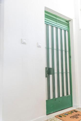 a green door on a white wall with a rug at 5 steps from the sea in Kalamata