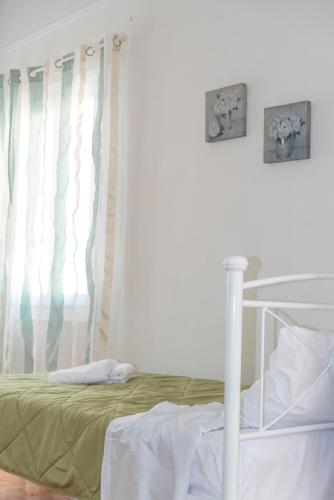 a bedroom with a bed with green sheets and a window at 5 steps from the sea in Kalamata