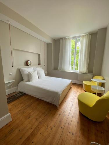 a bedroom with a white bed and a yellow chair at Château Bernon Maison d Hotes - Piscine et SPA in Queyrac