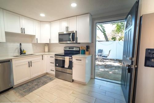 a kitchen with white cabinets and a stove top oven at Tranquil & Fully Renoveted Home Near Busch Gardens in Tampa