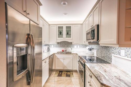 a kitchen with white cabinets and a stainless steel refrigerator at Upgraded and Spacious Harbor Towers Condo! Siesta Key Vacation! in Siesta Key