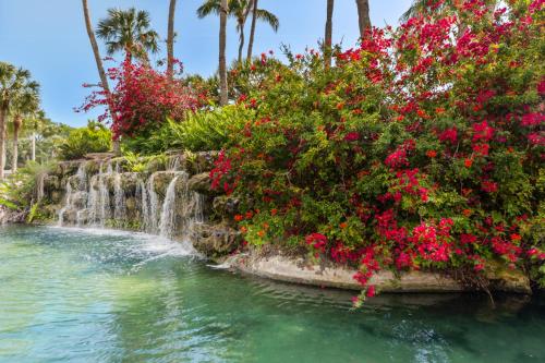 a waterfall and flowers in front of a body of water at Upgraded and Spacious Harbor Towers Condo! Siesta Key Vacation! in Siesta Key