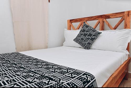 a bed with black and white sheets and pillows at Vivi Cafe B&B in Zanzibar City