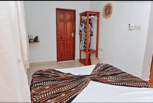 a bedroom with a bed and a wooden door at Vivi Cafe B&B in Zanzibar City