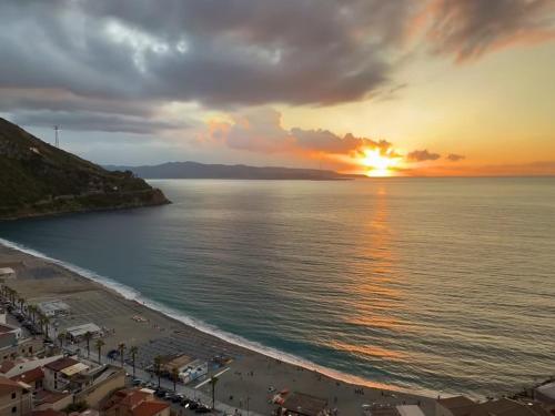 a view of a beach with the sun setting over the water at Casa Vacanze Belvedere in Scilla