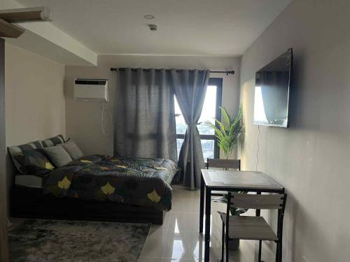 a living room with a bed and a table and a window at Sezuki JTower Stay in Mandaue City