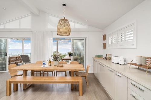 a kitchen and dining room with a wooden table at Drift - Ocean & Panoramic Views At Coledale in Coledale