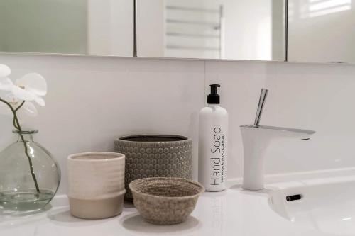 a bathroom counter with a bottle of soap and other items at Drift - Ocean & Panoramic Views At Coledale in Coledale