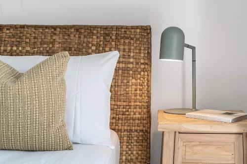 a bed with a pillow and a lamp on a night stand at Drift - Ocean & Panoramic Views At Coledale in Coledale