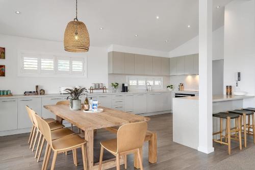 a kitchen with a wooden table and chairs at Drift - Ocean & Panoramic Views At Coledale in Coledale