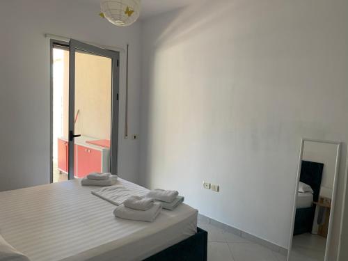 ein weißes Zimmer mit einem Bett, auf dem zwei Handtücher liegen in der Unterkunft Auras in Vlorë