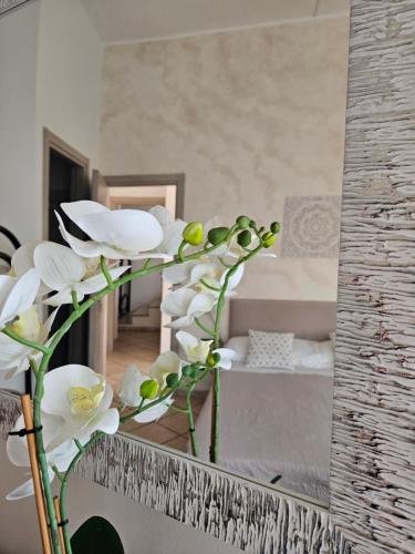 a vase with white flowers in front of a mirror at Dimora Sole del Sud in Ugento
