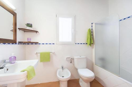 Un baño blanco con inodoro y lavabo. en Villa Dion Bosch Menorca, en Cala'n Bosch