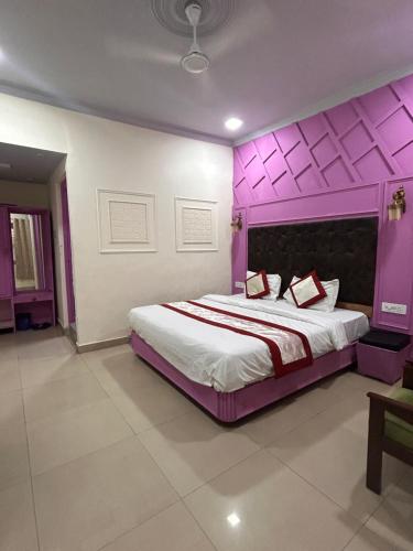 a bedroom with a large bed with a purple headboard at Hotel Amar in Mussoorie