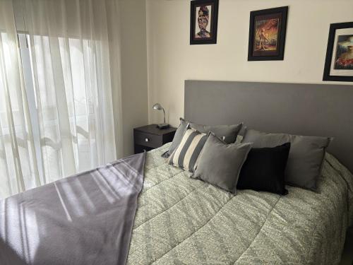 Un dormitorio con una cama con almohadas y una ventana. en Departamento en Mendoza confortable y tranquilo, en Godoy Cruz