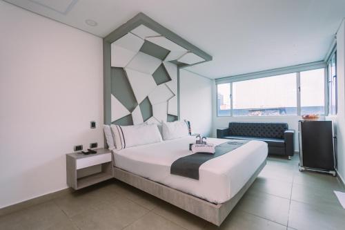 a hotel room with a large bed and a chair at Mandala Medellín Centro By GyC Hotels in Medellín
