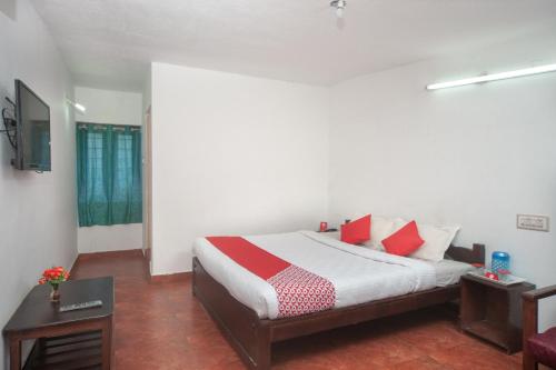 a bedroom with a bed with red and white pillows at Hotel O RGP Residency Kodaikanal lake in Kodaikānāl