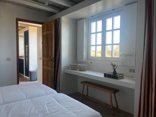 a bedroom with a bed and a window and a table at Casa de Campo in Vila Nova de Cacela