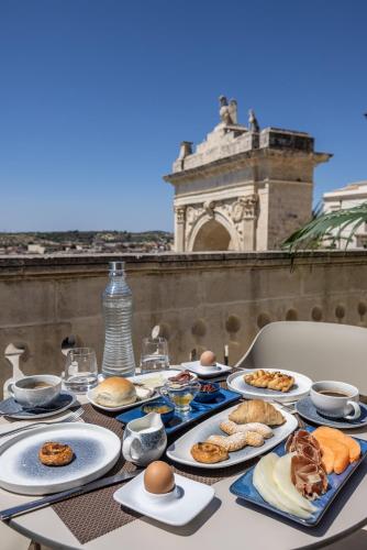 a table with plates of food on top of a building at Noto Boutique Hotel in Noto