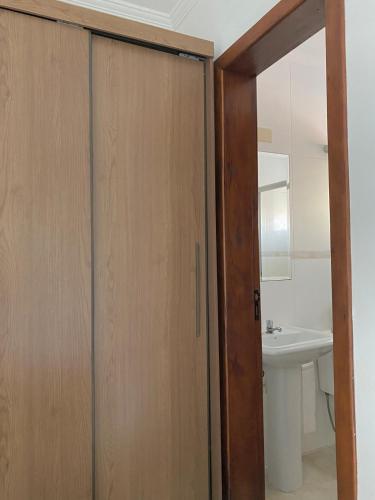 a bathroom with a wooden door and a sink at Duplex Acolhedor - Duas quadras do Mar Centro in Tramandaí