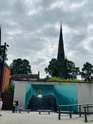 a building with a steeple in the background with a bench at Landvue Stays, Modern, 2 bed apartment with free parking! in Coventry