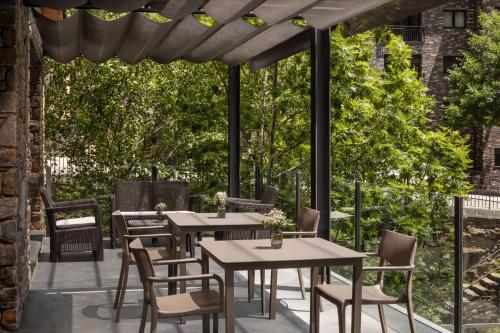 a patio with tables and chairs under a pergola at NH Collection Andorra Palomé in La Massana