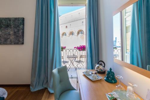 a room with a desk and a window with blue curtains at Palazzo Filisio - Regia Restaurant in Trani